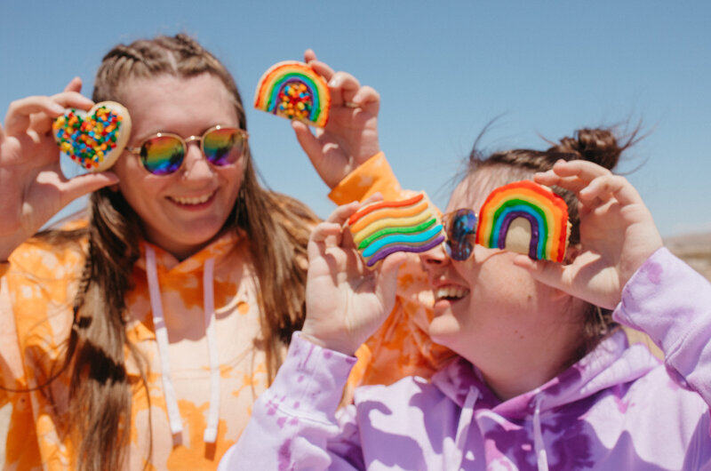 Two girls holding pride cookies.