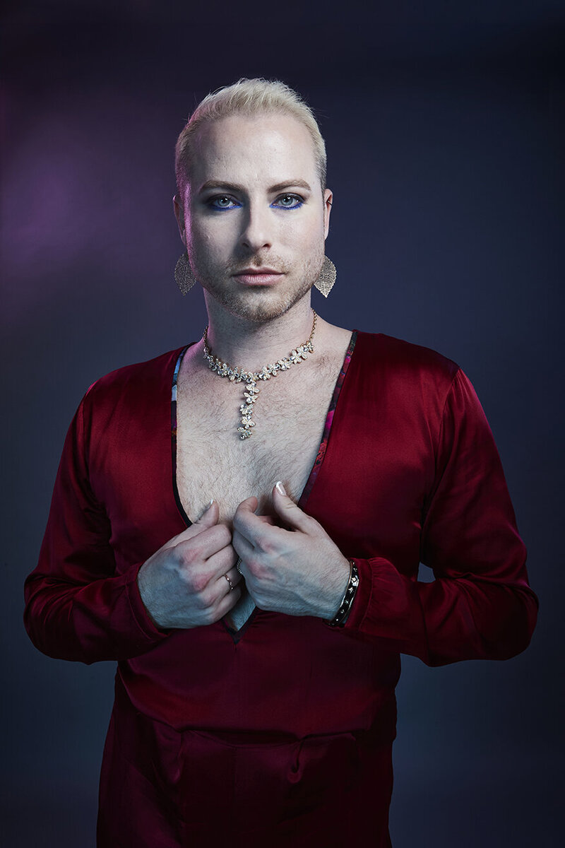 Studio close-up of Dain August in a red outfit, with bold lighting and a confident expression, captured by Ylva Erevall.