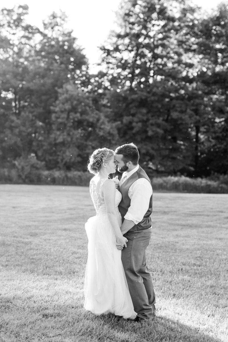 Bride and groom kissing in field