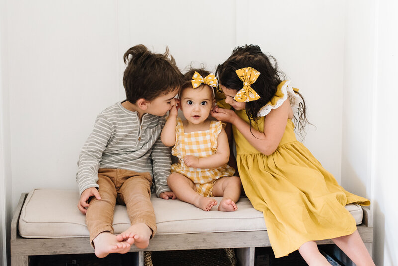 Three children in gray and yellow outfits with older children looking at toddler in center - Northern Virginia family photographer
