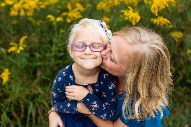 Mother kissing daugher's cheek during a family portrait session in Bonne Terre, Missour. 