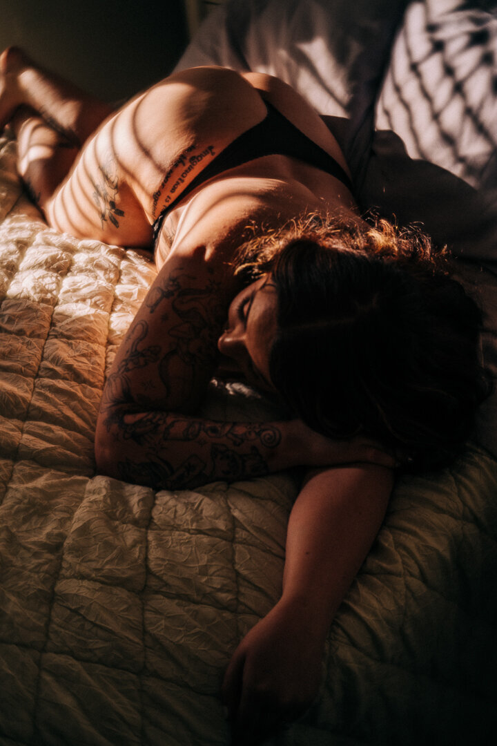 woman lying on a duvet cover with tattoos on her body