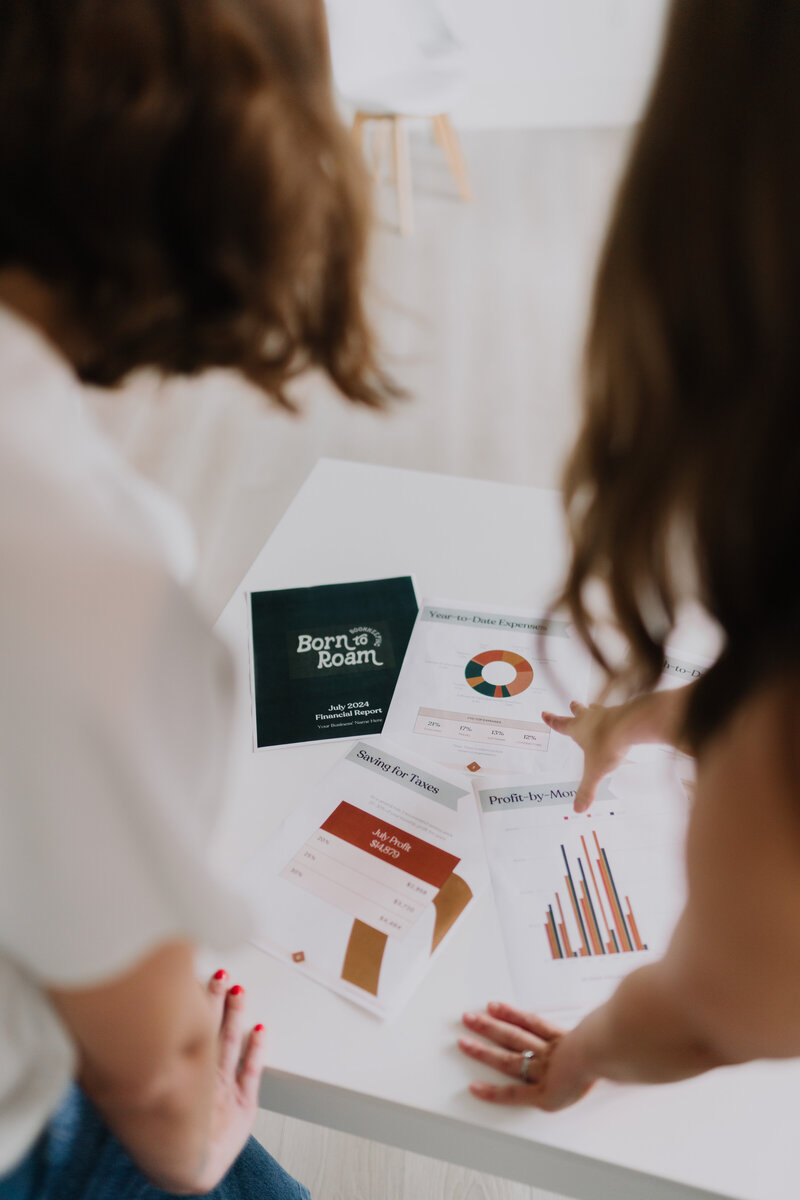 Two women looking at financial papers laying on a white table