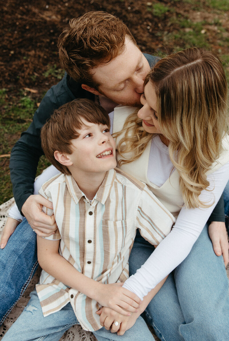 Family sitting on grass cuddling. 