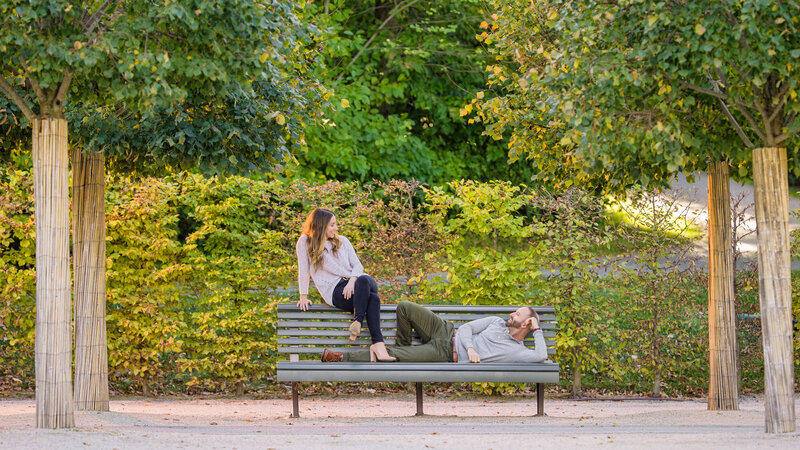 Couple sitting on a bench being quirky and playful during their Longwood Gardens engagement photography session.