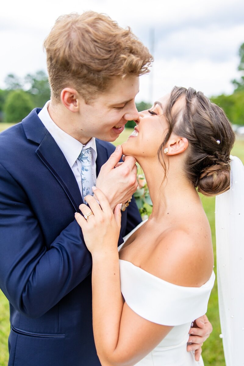 Groom gently lifting his brides chin as he leans in for a kiss