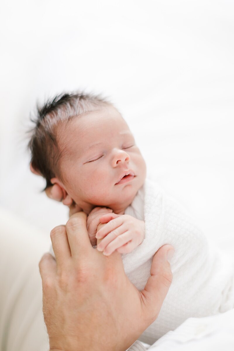A couple sits close together and gazes down at their newborn baby buring a newborn photo session in NJ.