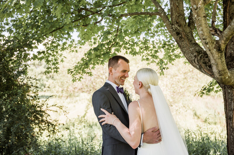 bride and groom laughing under a tree