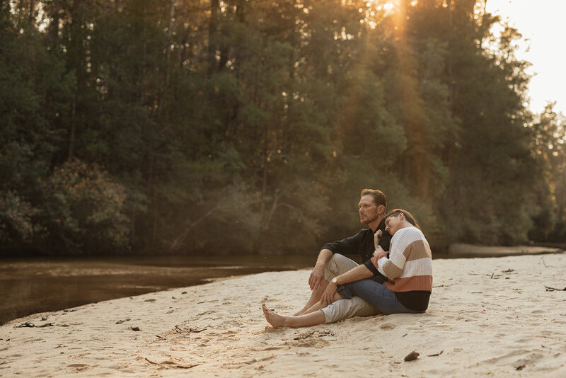 Bride and groom sitting and embracing each other in the sand, along a creek during golden hour in Florida
