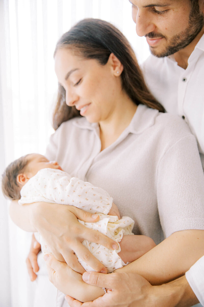 Een liefdevol moment tussen ouders en hun pasgeboren baby, vastgelegd in een serene en lichte omgeving.