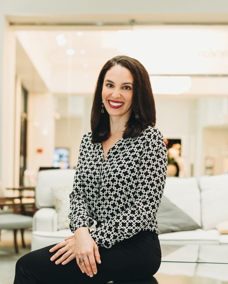 Betsy Castro smiles at the camera with an open book in hand. Contact a couples therapist in Florida for support today. An online therapist can provide it from the comfort of home!
