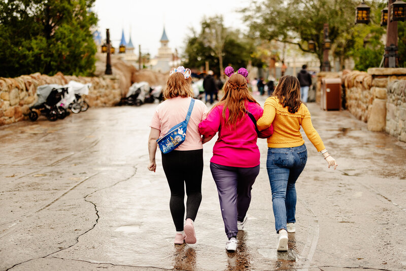 3 female entrepreneurs walk arm in arm through Disney World