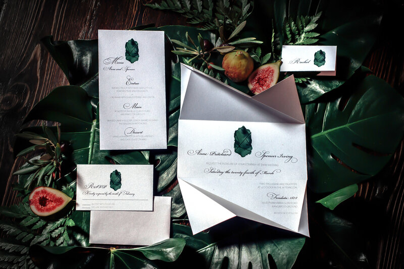 Green emerald wedding origami invitation suite on a dark moody backdrop