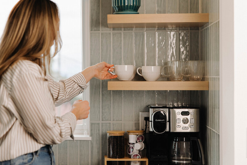 Woman reaching for a tea cup on a kitchen shelf