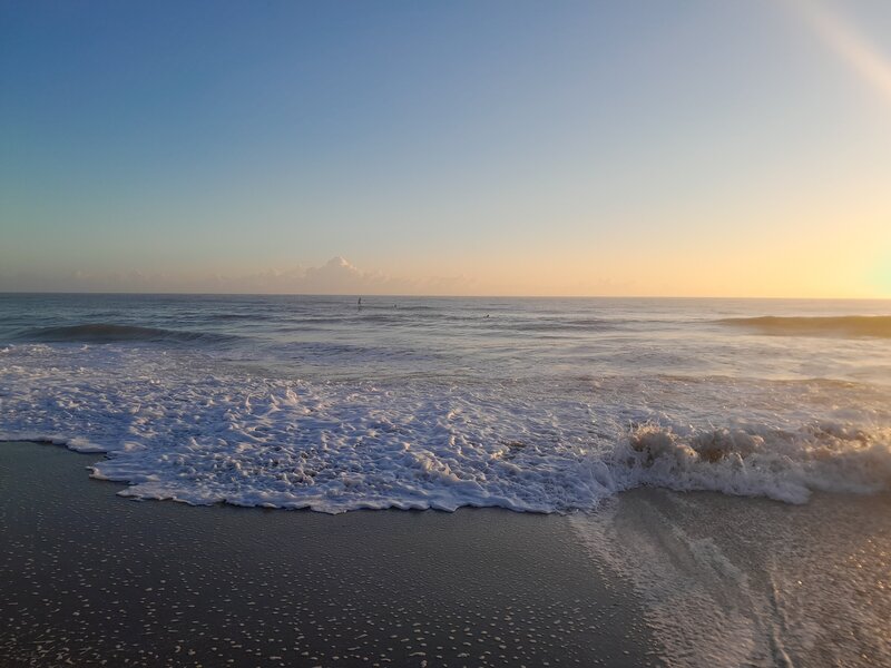 Older woman closes her eyes and stretches her arms for a yoga pose.