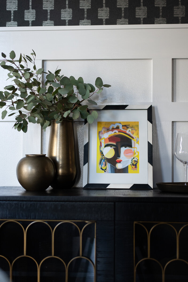 vases and artwork sitting on top of a dining room buffet