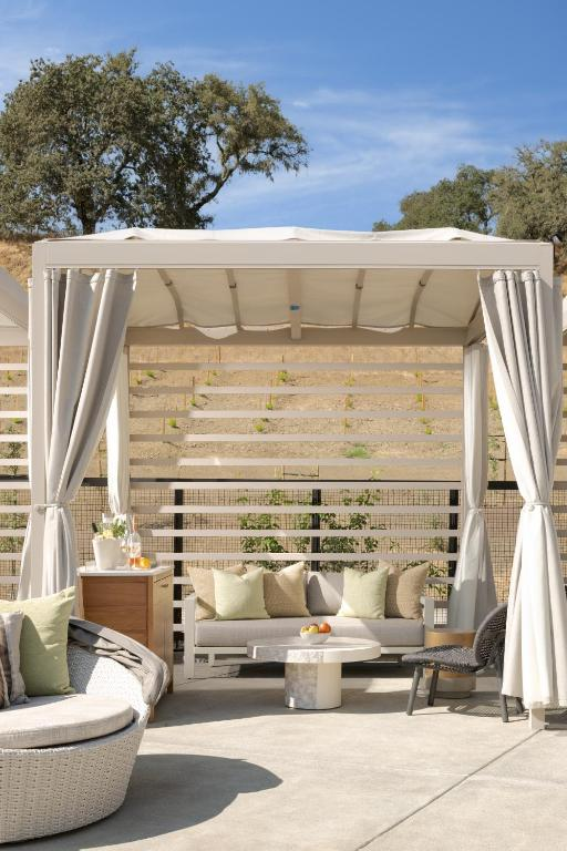 A bride and groom share a joyful moment pouring champagne into a tower of glasses, adorned with figs and grapes.