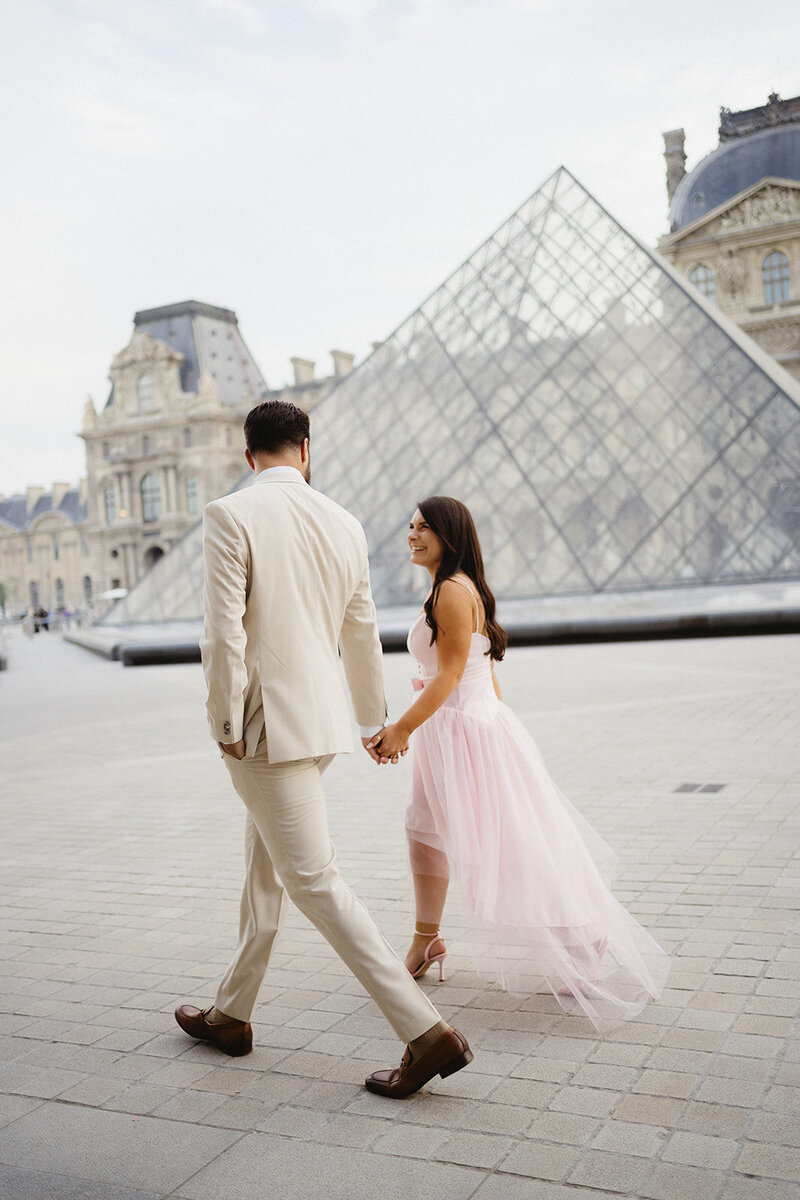 couple walking in front of the Louvre in Paris