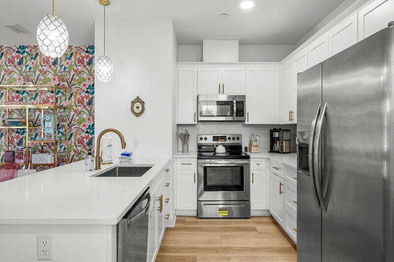 Modern vacation kitchen featuring stainless steel appliances, white cabinets, and pineapple pendant lights—steps from Carillon Beach and Santa Rosa Beach.