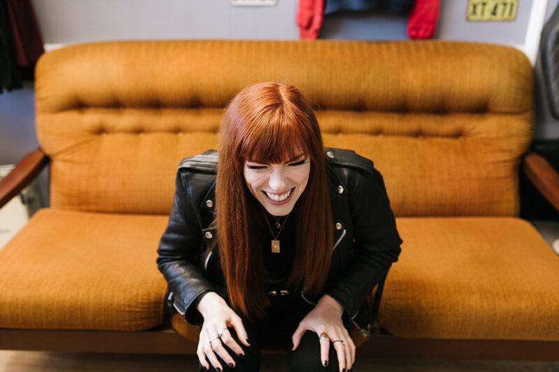 Image of redheaded girl laughing on mustard couch