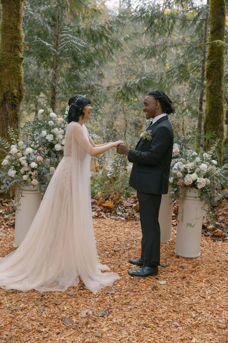 Bride and groom exchanging vows surrounded by floral arrangements
