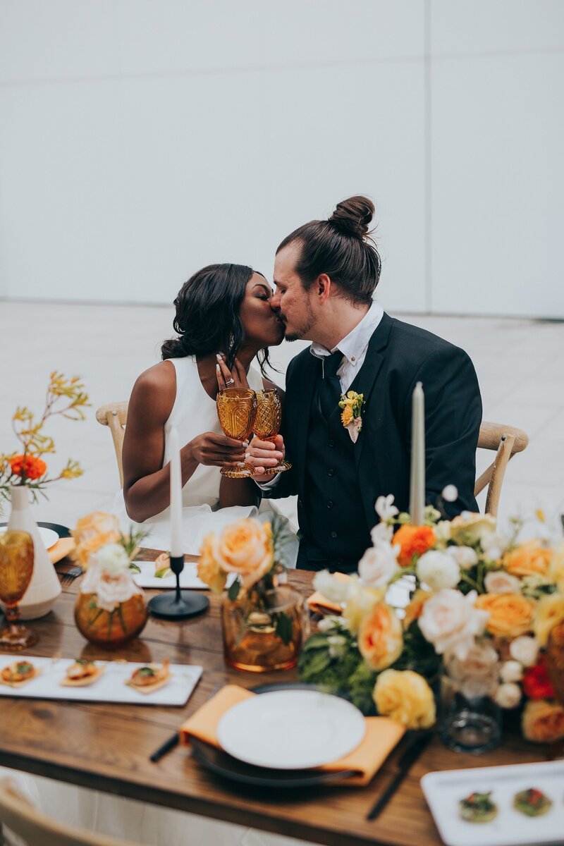 Couple kiss at sweetheart table at Dallas wedding
