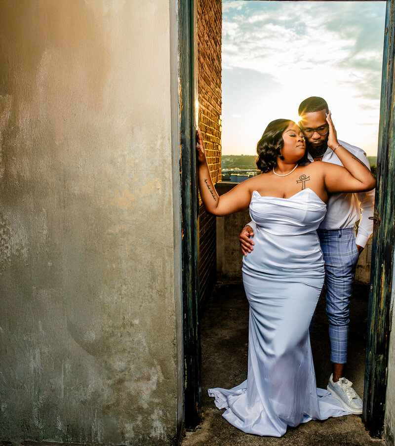 A stylish Black couple poses in chic formal attire on a sidewalk covered in golden leaves, showcasing elegance and love in this breathtaking outdoor portrait.