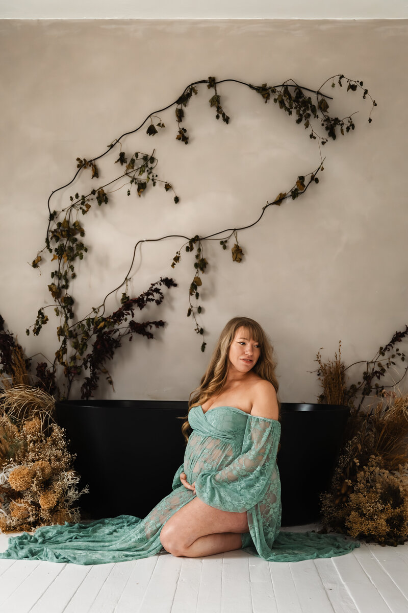 Expecting mother posing in a studio setting, captured in a soft and elegant maternity portrait that highlights the beauty of pregnancy.