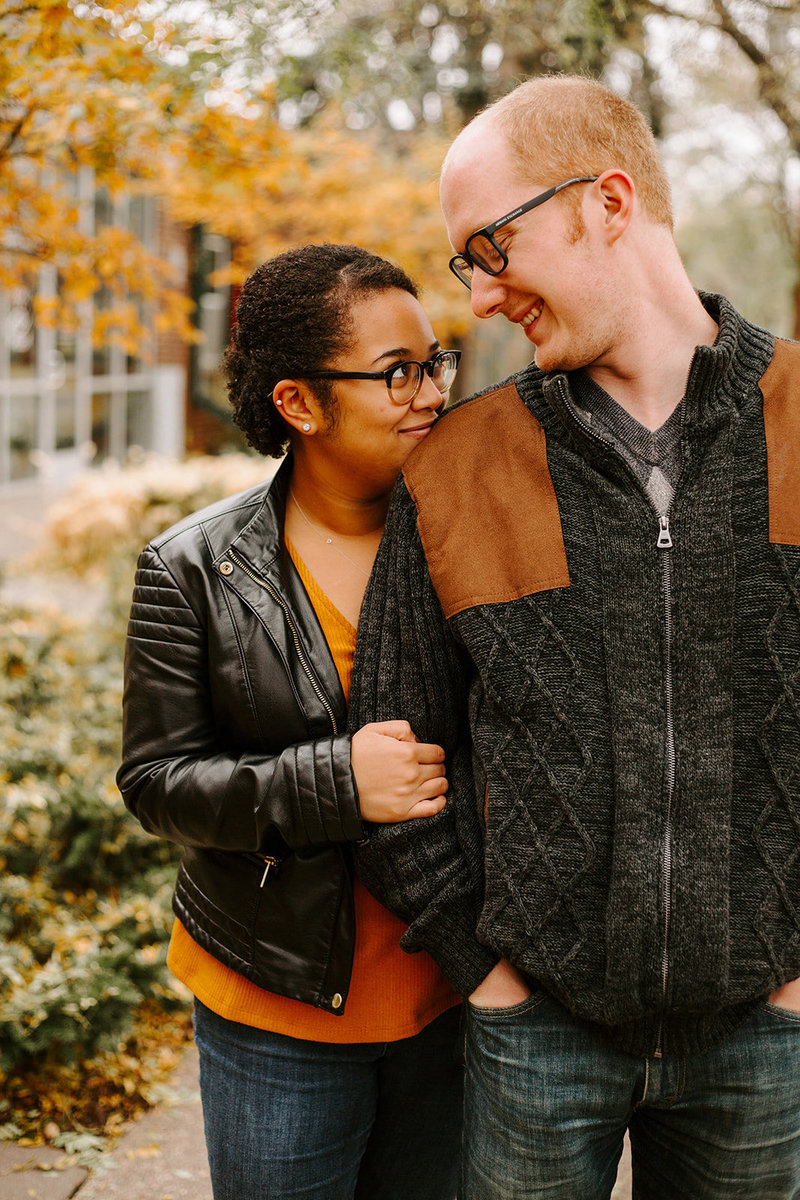 Girl holding the guys arm and smiling at each other during their Minneapolis engagement session
