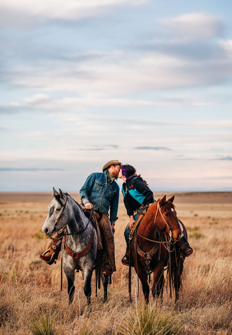 couple on their horses leaning in for a kiss