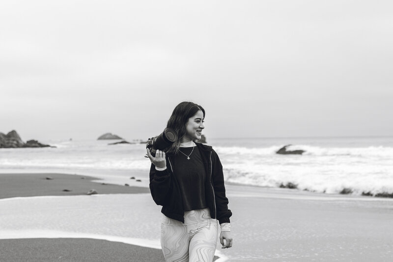 Karen Michelle walking on the beach with camera, candid brand photo for photographer bio