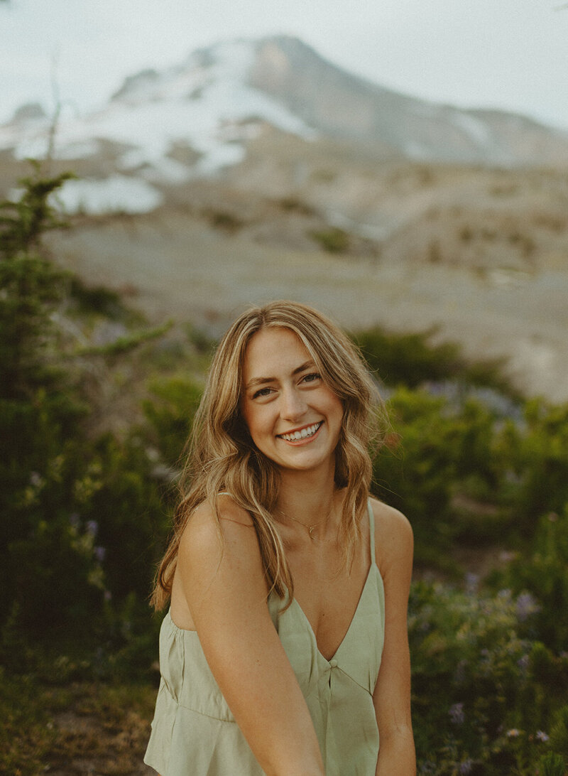 senior portrait headshot of girl in green tank top in front of mountainside