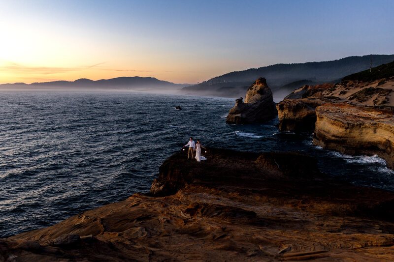 Couple sitting by the ocean during golden hour, highlighting natural beauty with an Oregon Coast Elopement and Wedding Photographer.