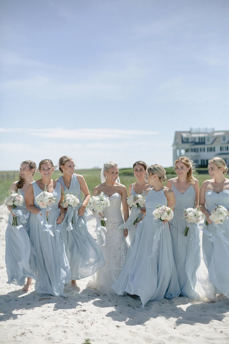 Bridesmaids walk on beach in blue dress during Cape Cod wedding. East Coast Wedding Photography by  Deborah Zoe Photography.