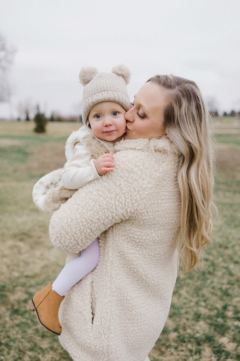 mom kissing daughter's cheek during tree farm family session