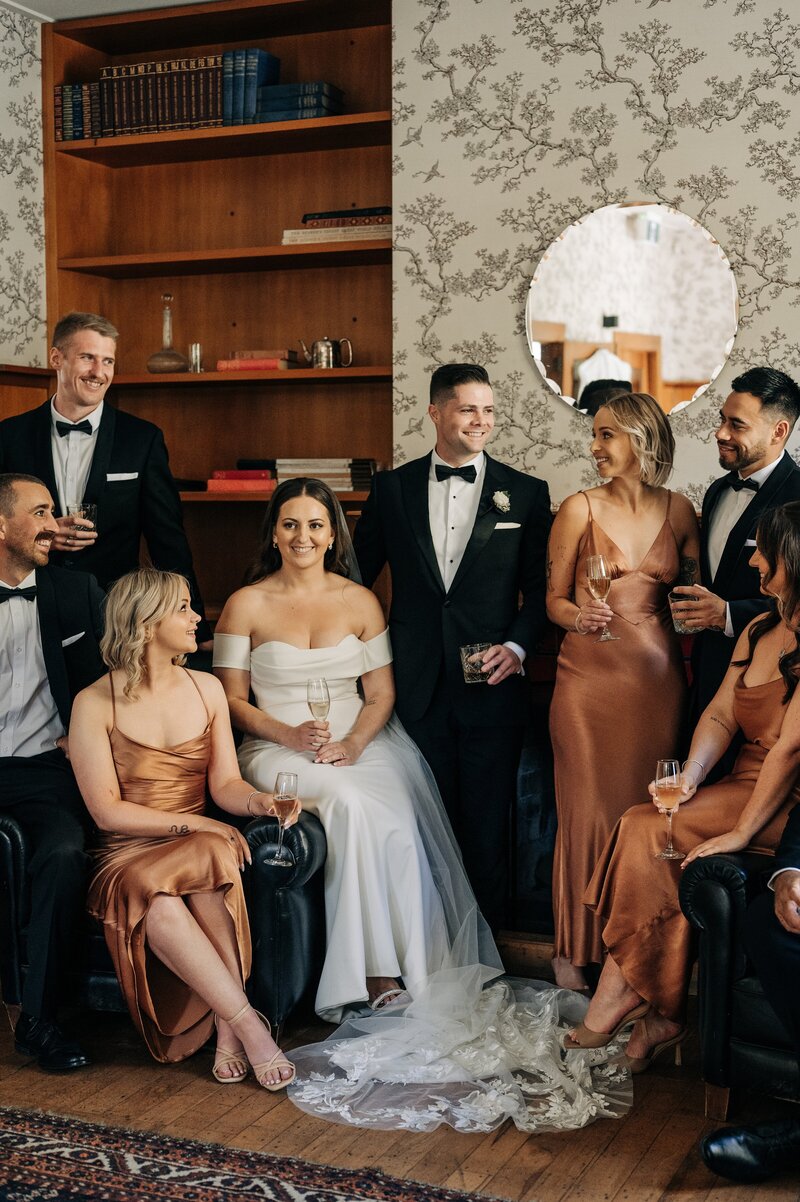 vogue inspired photo of wedding party in rust colour dress in whiskey room at the winehouse queenstown