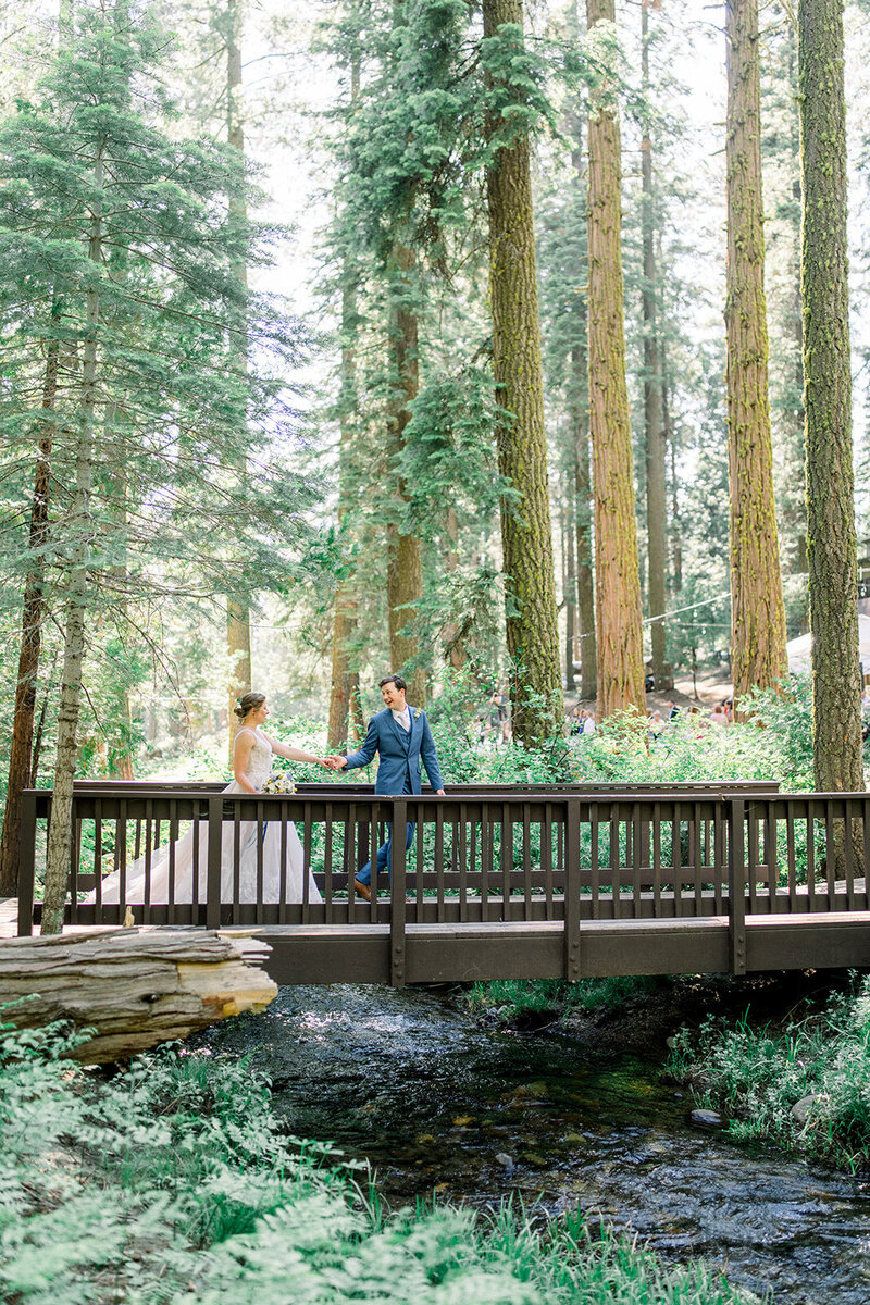 Tiffany Longeway Photography beautifully captures a couple’s romantic moment on a rustic bridge surrounded by the towering redwoods of California. The lush greenery and serene stream below add to the magical and intimate atmosphere, perfect for couples seeking a natural and picturesque setting for their wedding photographs. This image showcases the unique charm of outdoor weddings that integrate the grandeur of California’s natural landscapes.