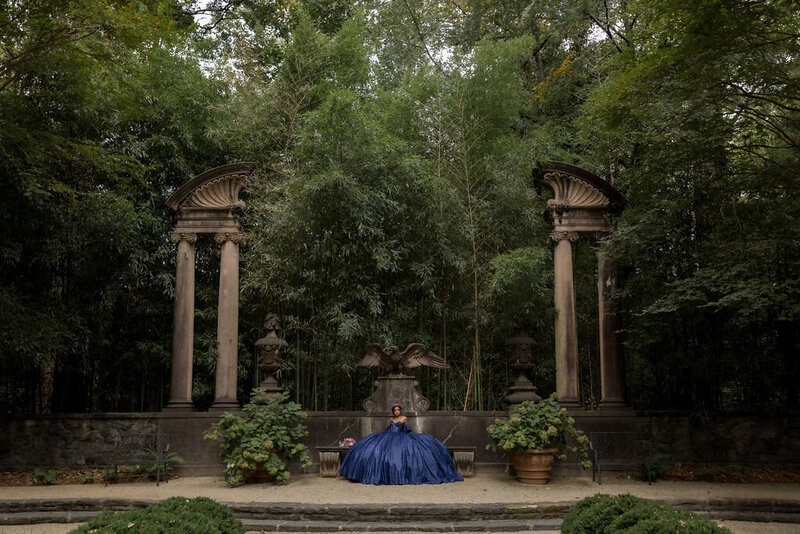 woman in quinceanera dress standing in front of large stone building