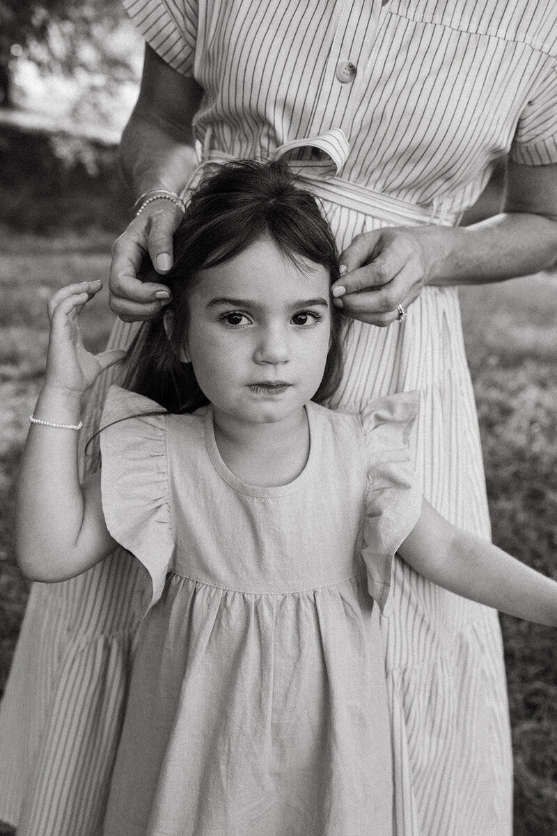 Mother gently brushing her toddler daughter’s bangs out of her face during an in-home lifestyle family photography session