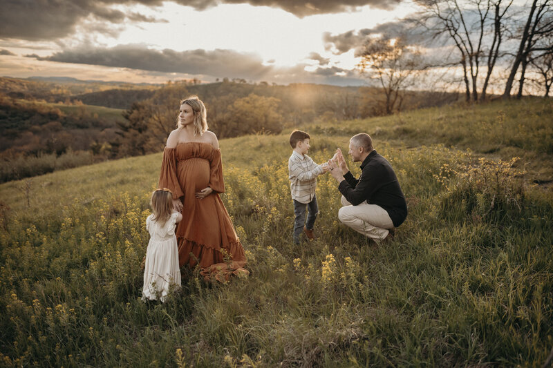family maternity session in field of wildflowers at sunset