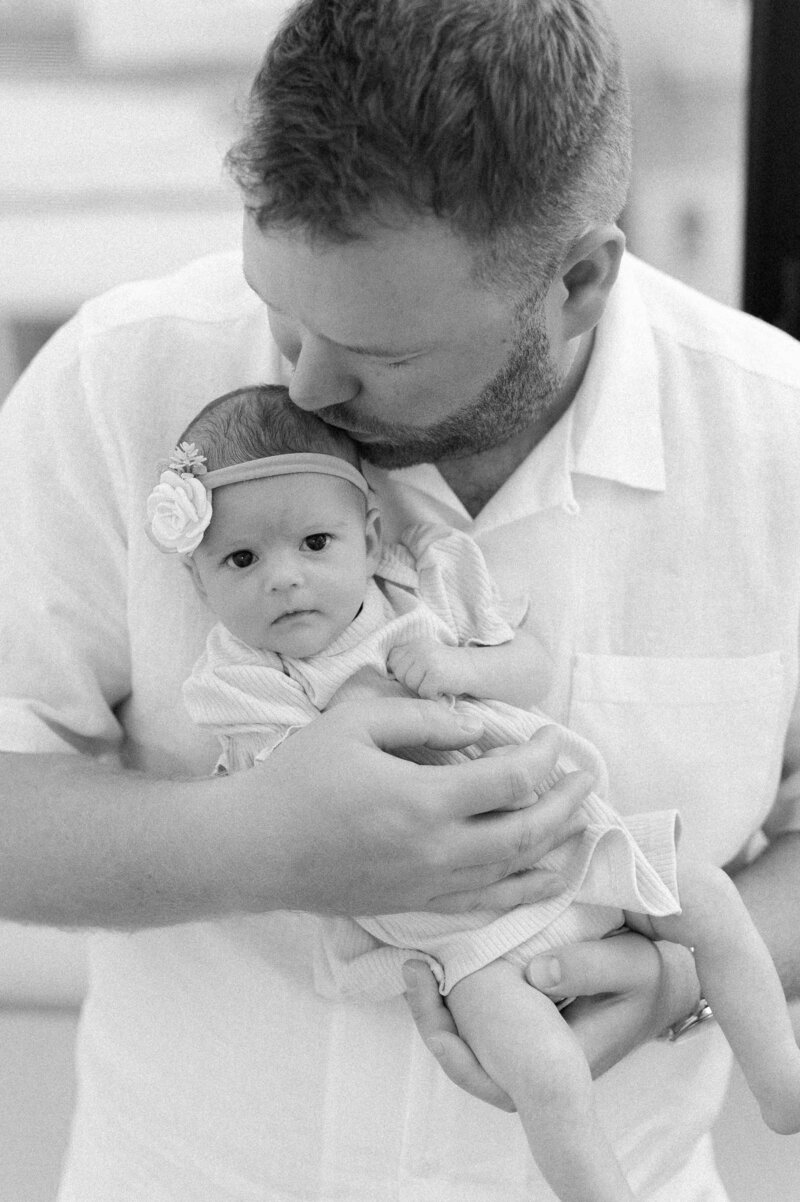 Dad kissing his daughter lovingly while posing for family photos in Los Angeles.