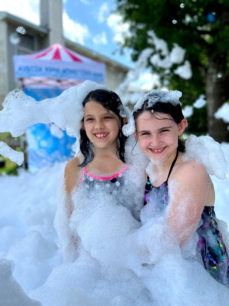 two friends smile as they play in the foam