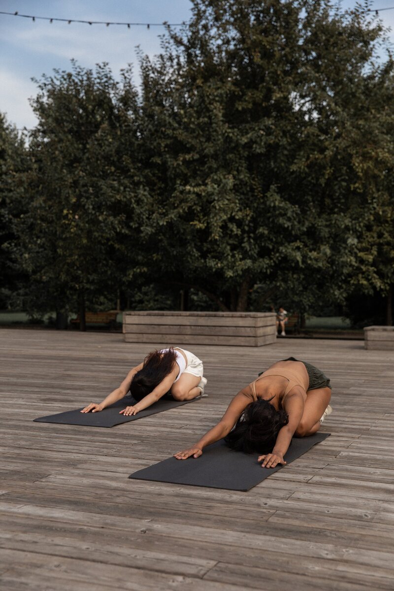 two girls doing yoga and posing in childs pose