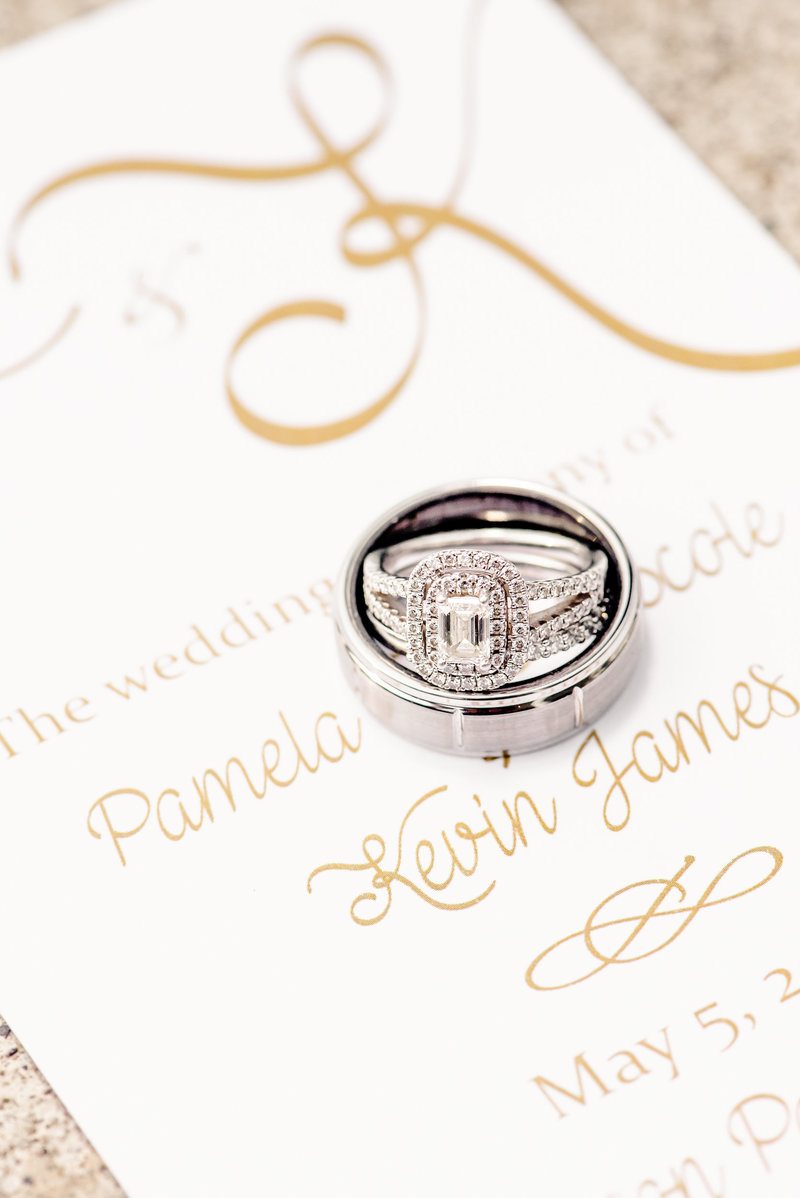 WEdding rings placed on top of a wedding invitation
