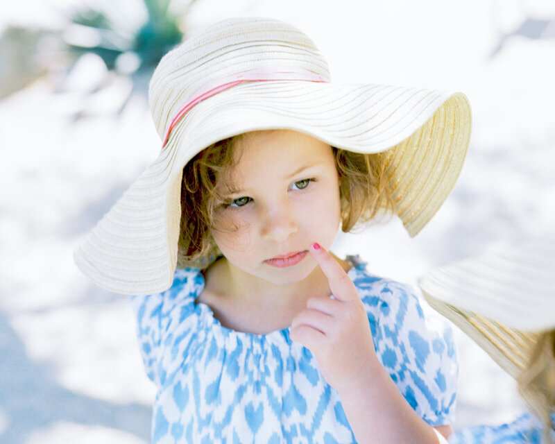 Chicago  newborn photographer captures a portrait of a young girll in a blue and white shirt wearing a sunhat