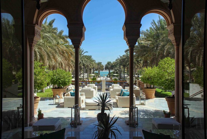 Elegant open-air lounge framed by Moorish arches, overlooking a palm-lined pathway leading to the sea at One&Only The Palm in Dubai, United Arab Emirates ©Stephanie Dosch | theViatrix Luxury Travel