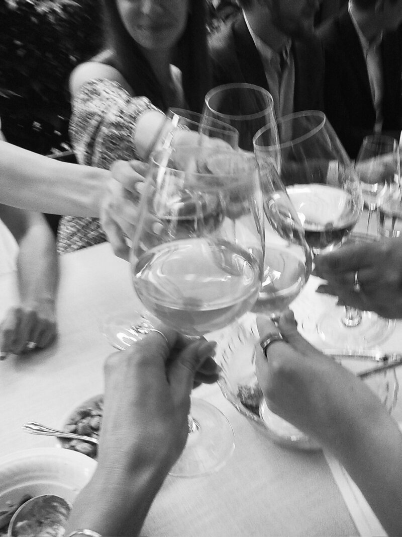 A black and white photo of a friend group clinking drinks
