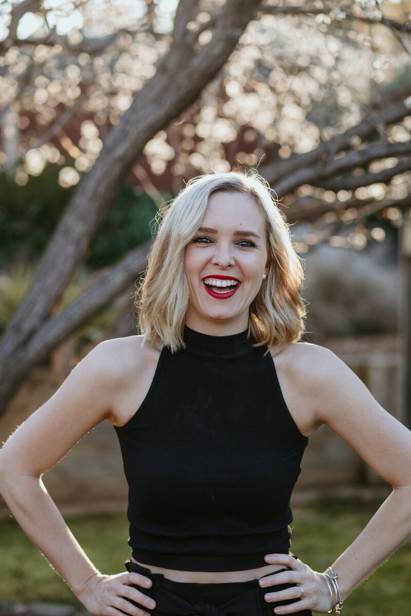 Tanya Strauss, Bendigo wedding and portrait photographer, laughing in black outfit with red lips