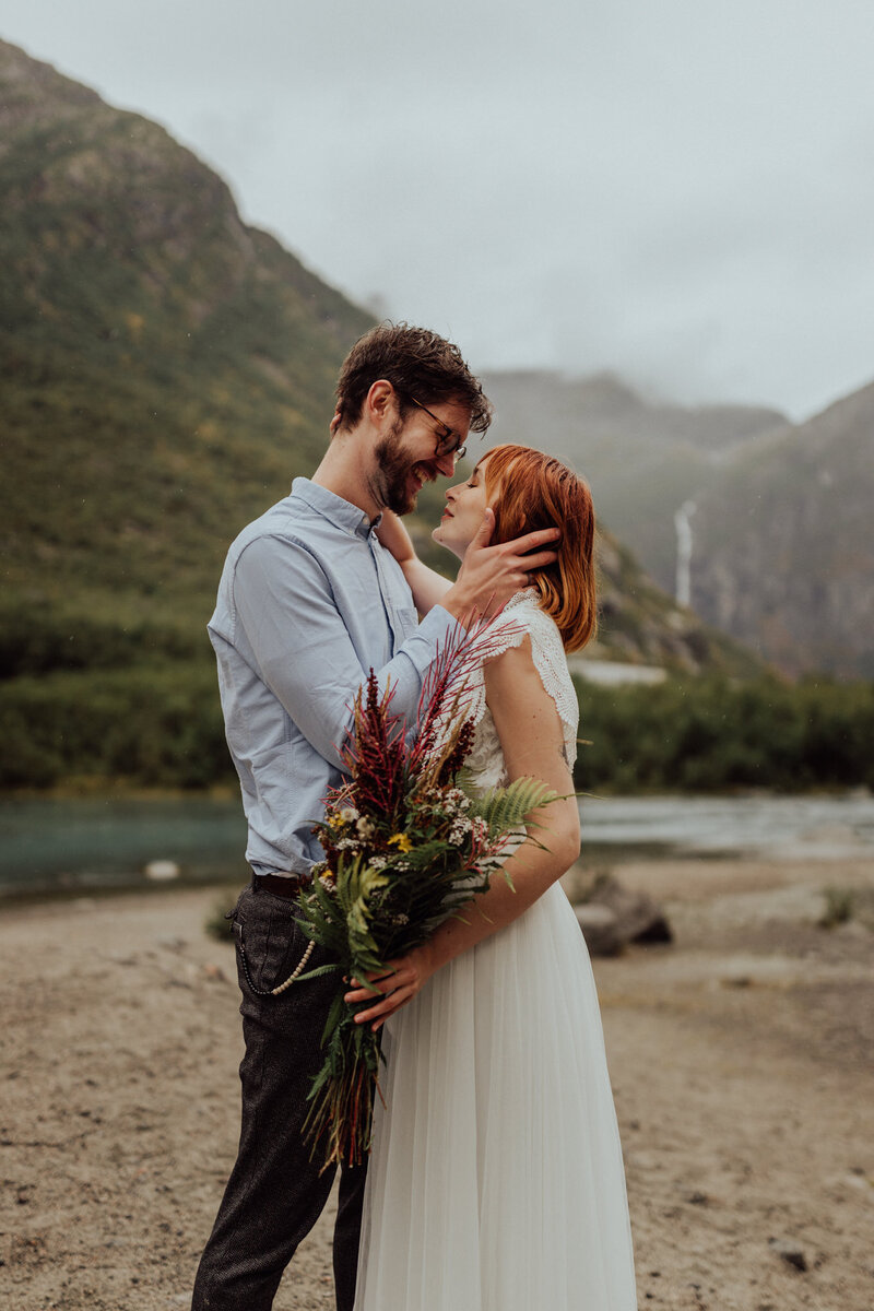 a couple in wedding attire kiss at sunrise in front of the Hintersee in the German Alps