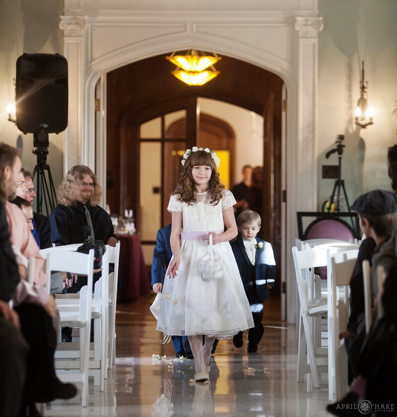 Flower girl walks down the aisle inside the Solarium Room at Highlands Ranch mansion